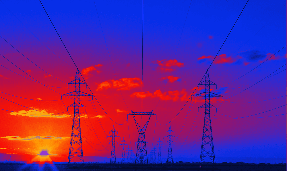 Voltage power lines and pylons against a vibrant sunset sky.