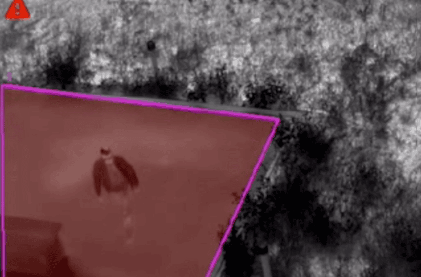 Surveillance camera capturing a person outdoors at night for security purposes.